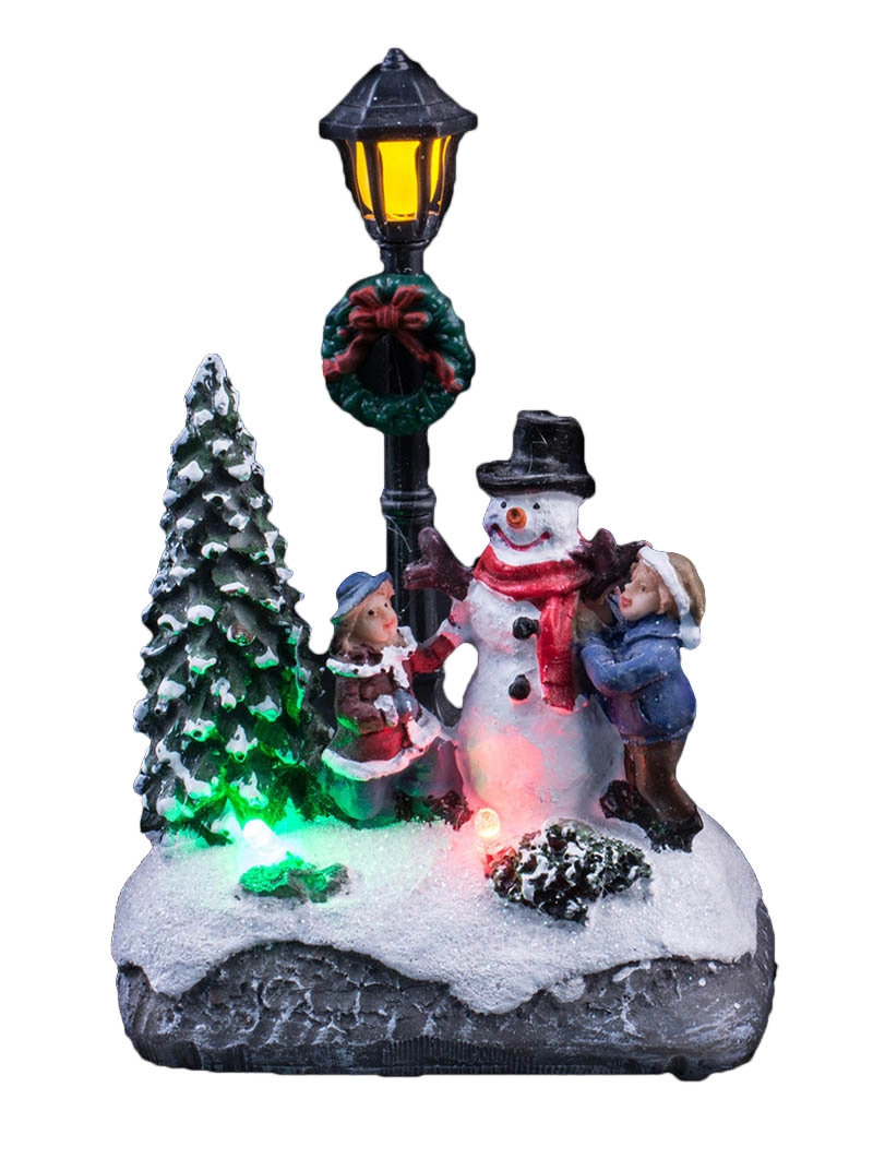 La scena di Natale illuminata con i bambini decora il pupazzo di neve
